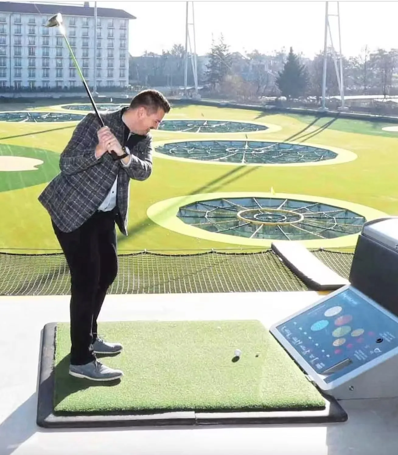 Abschlag in einer Topgolf-Bay mit Blick auf das Außenfeld